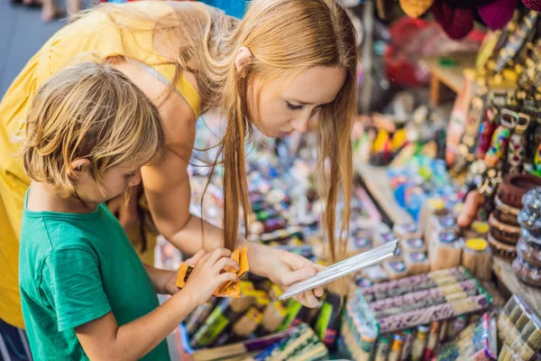 Mamá e hijo viajeros eligen recuerdos en el mercado en Ubud en Bali, Indonesia —  Fotos de Stock