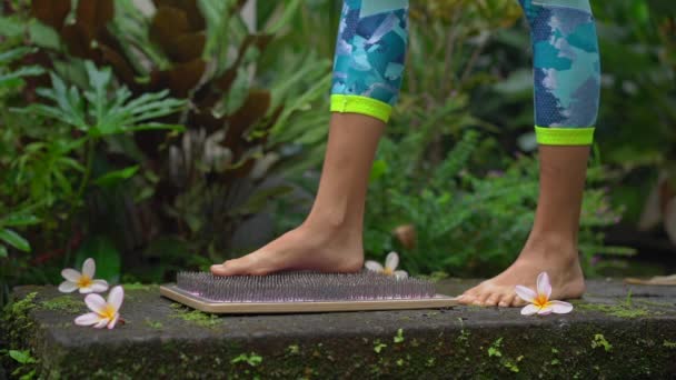 Медленный снимок молодой женщины, использующей доску Садху или гвоздь в тропической среде — стоковое видео