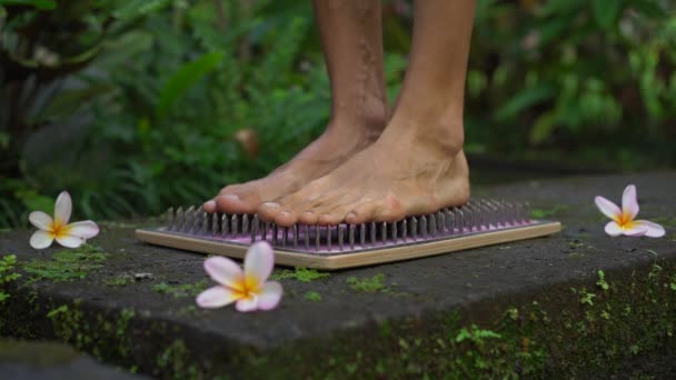 Zeitlupenaufnahme eines jungen Mannes, der ein Sadhu-Brett oder Nagelbrett in einer tropischen Umgebung benutzt — Stockvideo