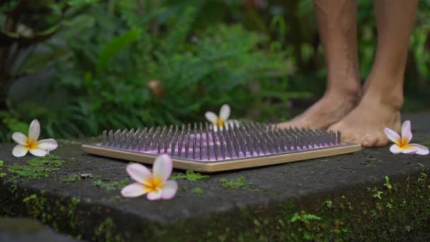 Fotografía en cámara lenta de un joven que usa una tabla Sadhu o una tabla de clavos en un entorno tropical — Vídeos de Stock