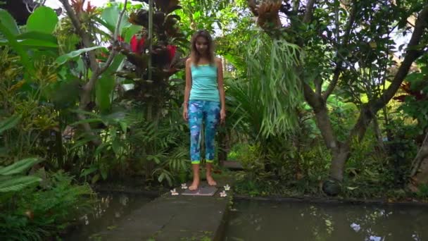 Медленный снимок молодой женщины, которая не может наступить на доску Садху или ногтевую доску в тропических окрестностях — стоковое видео