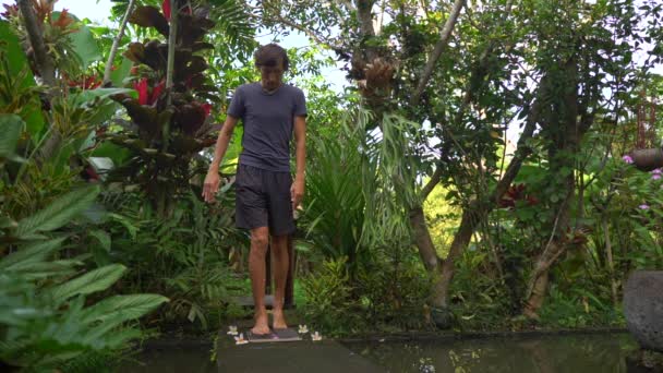 Slowmotion shot van een jonge man die een Sadhu-bord of een nagel plank in een tropische omgeving gebruikt — Stockvideo