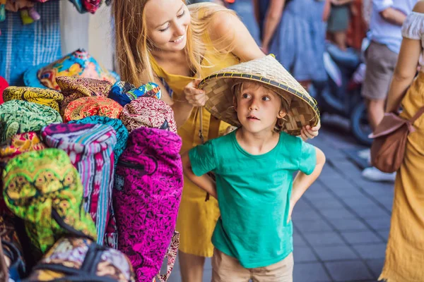 Mamma och son resenärer väljer souvenirer på marknaden i Ubud i Bali, Indonesien — Stockfoto