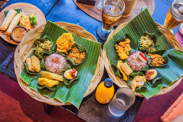 Nasi lemak, Nasi campur, arroz balinês indonésio com batata frita, lilit saciado, tofu frito, ovos picantes cozidos e amendoim — Fotografia de Stock