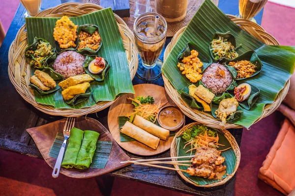 Nasi lemak, nasi campur, indonesischer balinesischer Reis mit Kartoffelfritter, Satellilit, gebratenem Tofu, pikant gekochten Eiern und Erdnüssen — Stockfoto