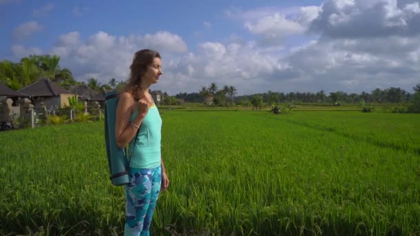 Медленная съемка молодой женщины, занимающейся йогой, идущей по красивому рисовому полю. — стоковое видео