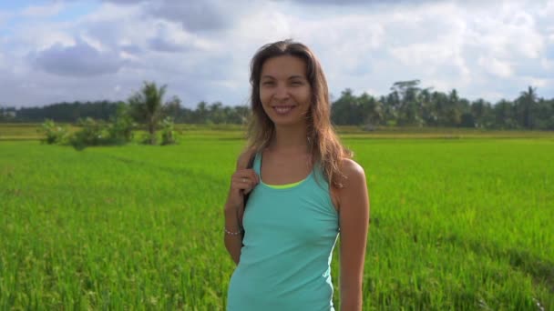 Slowmotion steadicam shot d'une jeune femme avec des mathématiques de yoga marchant à travers un beau champ de riz — Video