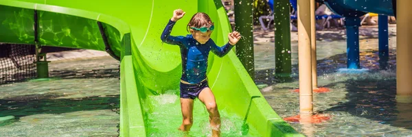 Niño feliz en el tobogán acuático en una piscina que se divierte durante las vacaciones de verano en un hermoso complejo tropical BANNER, FORMATO LARGO — Foto de Stock