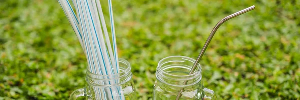 Steel drinking vs disposable straws on grass background. Zero waste concept BANNER, LONG FORMAT