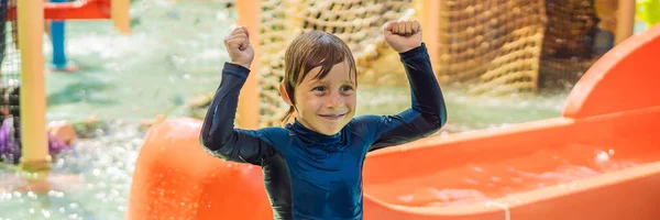 Niño feliz en el tobogán acuático en una piscina que se divierte durante las vacaciones de verano en un hermoso complejo tropical BANNER, FORMATO LARGO —  Fotos de Stock