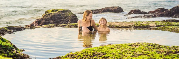 BANNER, FORMAT LONGUE Des touristes de mère et fils sur la plage de Pantai Tegal Wangi, assis dans un bain d'eau de mer, île de Bali, Indonésie. Bali Travel Concept. Voyager avec des enfants concept. Enfants sympathiques — Photo