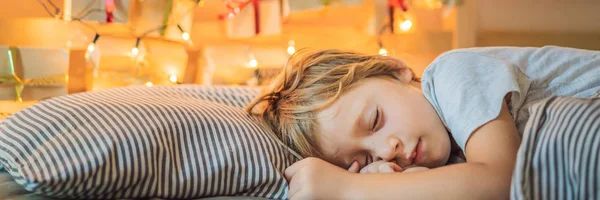 Mały blond chłopiec śpi na łóżku i domu wykonane Kalendarz adwentowy na półce. Zima sezonowych tradycji. Kopiuj przestrzeń banner, długi format — Zdjęcie stockowe