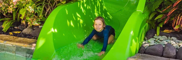 Menino feliz em toboágua em uma piscina se divertindo durante as férias de verão em um belo resort tropical BANNER, LONG FORMAT — Fotografia de Stock