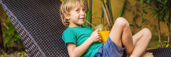 Chico bebiendo jugoso batido de mango en tarro de cristal de albañil con paja de acero en el fondo de la piscina. Concepto de vida saludable, espacio de copia BANNER, FORMATO LARGO —  Fotos de Stock