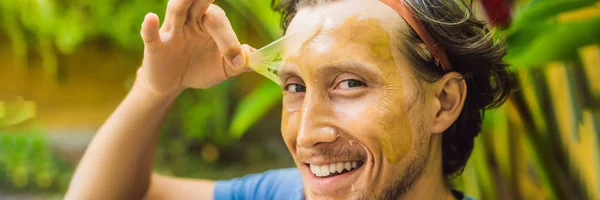 Young handsome man makes a green cosmetic face mask. Skin Care for Men Concept BANNER, LONG FORMAT — Stock Photo, Image