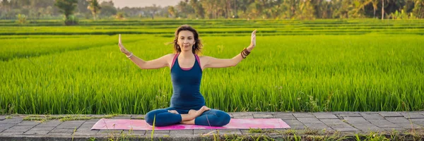 Junge Frau praktiziert Yoga im Freien in Reisfeldern am Morgen während eines Wellness-Retreats in Bali-Banner, Langformat — Stockfoto