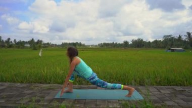 Güzel bir pirinç tarlasında yoga yapan genç bir kadının slowmotion çekimi