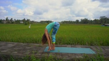Güzel bir pirinç tarlasında yoga yapan genç bir kadının slowmotion çekimi