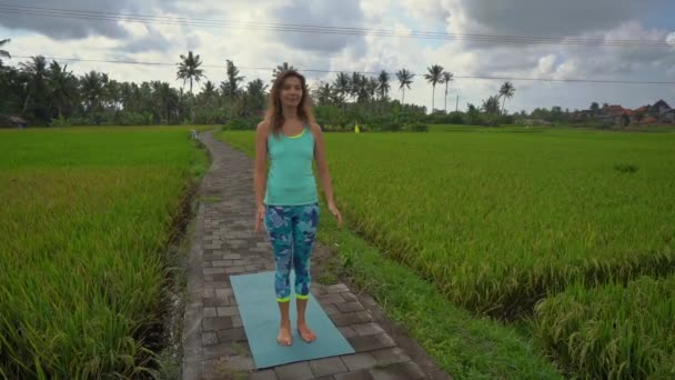 Slowmotion Steadicam geschoten van een jonge vrouw beoefenen van yoga op een prachtig rijstveld — Stockvideo