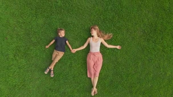 Çimlerin üzerinde yatan genç bir kadın ve oğlunun havadan çekilmiş fotoğrafı — Stok video