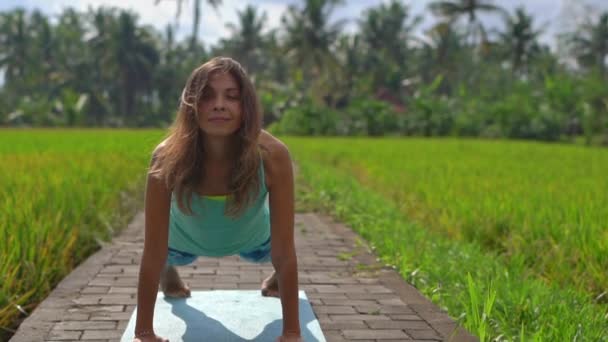 Zeitlupenaufnahme einer jungen Frau, die Yoga auf einem schönen Reisfeld praktiziert — Stockvideo
