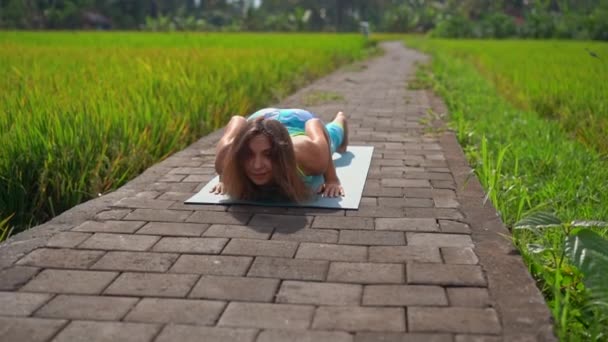 Повільний знімок молодої жінки, що практикує йогу на красивому рисовому полі — стокове відео
