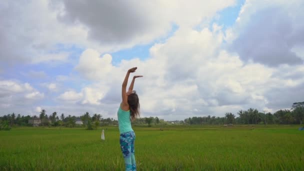 一个年轻女子在美丽的稻田上练习瑜伽的慢动作镜头 — 图库视频影像