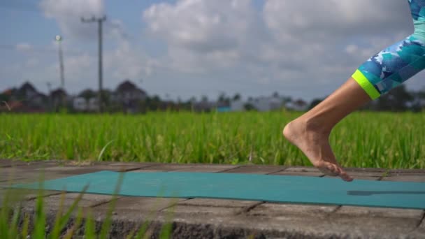 Slowmotion tiro de uma jovem mulher praticando ioga em um belo campo de arroz — Vídeo de Stock