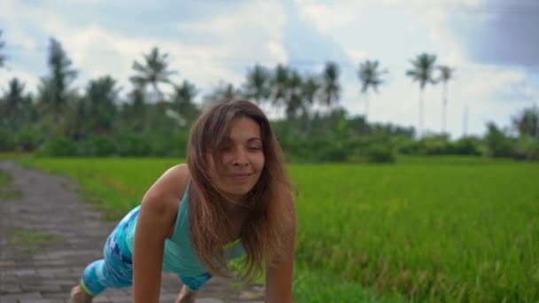 Повільний знімок молодої жінки, що практикує йогу на красивому рисовому полі — стокове відео