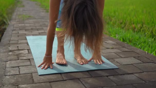 Slowmotion tiro de uma jovem mulher praticando ioga em um belo campo de arroz — Vídeo de Stock