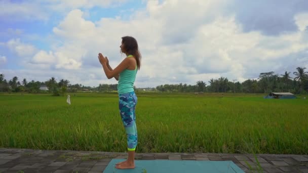 Zeitlupenaufnahme einer jungen Frau, die Yoga auf einem schönen Reisfeld praktiziert — Stockvideo