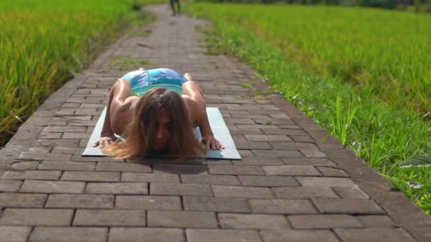 Slowmotion shot van een jonge vrouw die yoga beoefenen op een prachtig rijstveld — Stockvideo