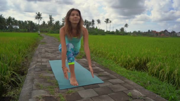 Slowmotion tiro de uma jovem mulher praticando ioga em um belo campo de arroz — Vídeo de Stock