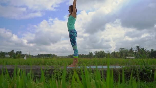 Slowmotion steadicam tiro de uma jovem praticando ioga em um belo campo de arroz — Vídeo de Stock