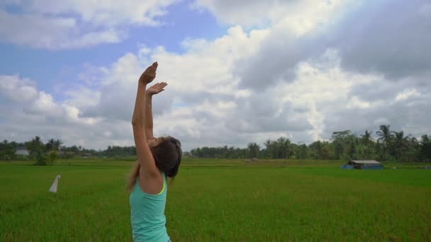Slowmotion steadicam shot d'une jeune femme pratiquant le yoga sur un beau champ de riz — Video