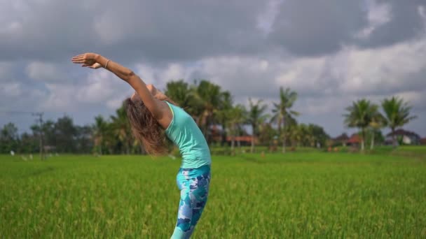 Медленный снимок молодой женщины, практикующей йогу на красивом рисовом поле — стоковое видео