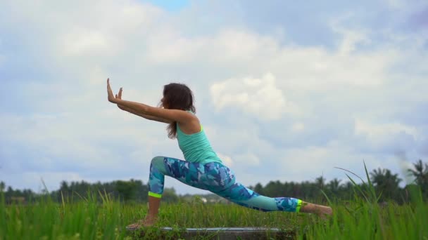 Slowmotion skott av en ung kvinna som tränar yoga på ett vackert risfält — Stockvideo