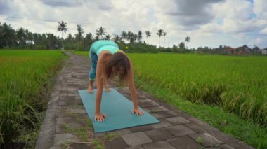 Güzel bir pirinç tarlasında yoga yapan genç bir kadının slowmotion çekimi