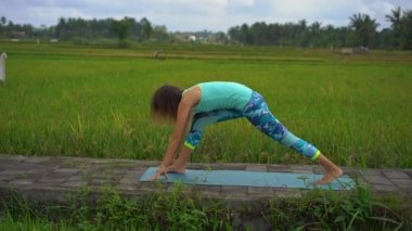 Güzel bir pirinç tarlasında yoga yapan genç bir kadının slowmotion çekimi