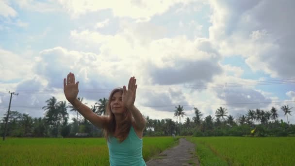 Slowmotion colpo steadicam di una giovane donna con matematica yoga a piedi attraverso una bella risaia — Video Stock