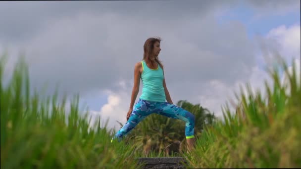 Plan au ralenti d'une jeune femme pratiquant le yoga sur un beau champ de riz — Video