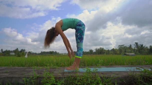 Slowmotion steadicam toma de una joven practicando yoga en un hermoso campo de arroz — Vídeo de stock
