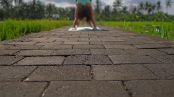 Slowmotion steadicam toma de una joven practicando yoga en un hermoso campo de arroz — Vídeo de stock