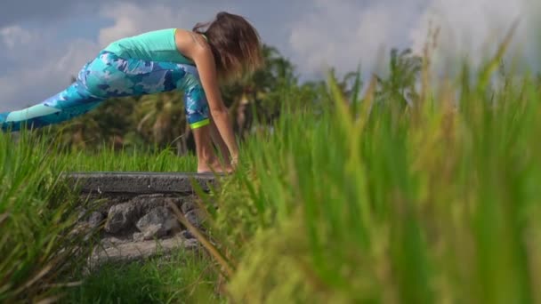美しい田んぼでヨガを練習している若い女性のスローモーションショット — ストック動画