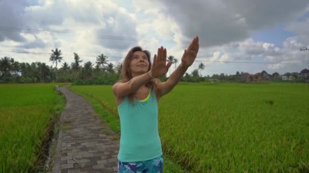 Медленная съемка молодой женщины, практикующей йогу на красивом рисовом поле — стоковое видео
