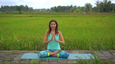 Bali bir şekilde Muladhara çakra için meditasyon yapan genç bir kadının Slowmotion steadicam çekim