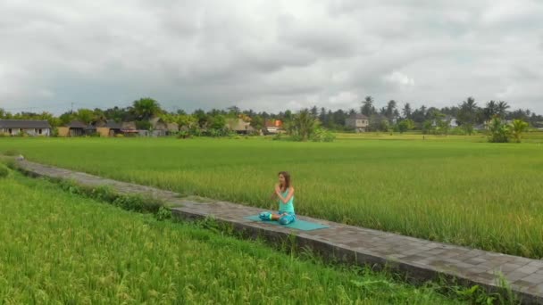 Медленная воздушная съемка молодой женщины, медитирующей на чакру Муладхары балийским способом — стоковое видео