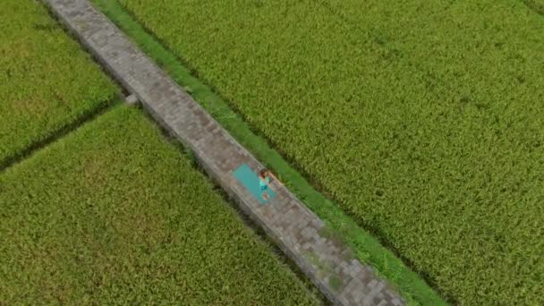 Foto en cámara lenta aérea de una joven practicando yoga en un hermoso campo de arroz — Vídeo de stock