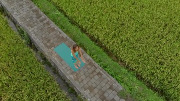 Aerial Slowmotion shot di una giovane donna che pratica yoga su una bella risaia — Video Stock