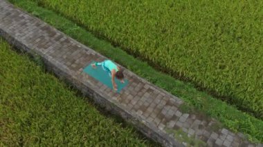 Güzel bir pirinç tarlasında yoga yapan genç bir kadının Havadan Slowmotion çekimi